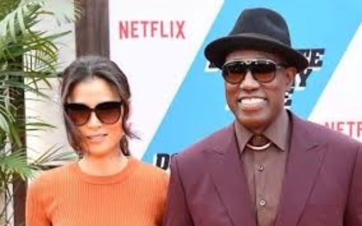 Nakyung wearing orange dress and her husband wearing a black hat.